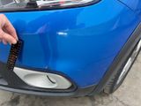 a person holding a remote control in front of a blue car