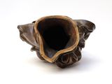 a brown vase with a flower inside of it on a white surface
