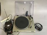 une platine vinyle avec un lecteur de disques et d'autres appareils électroniques posés sur la table
