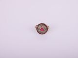 a close up of a red stone ring on a white surface