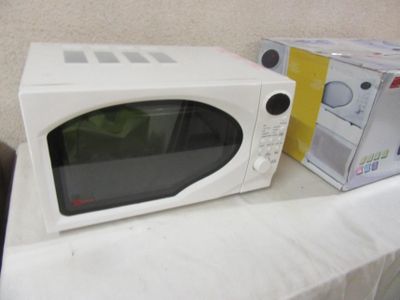 a white microwave sitting on a table next to a box