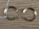 une paire de boucles d'oreilles créoles en or posée sur une table