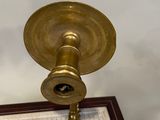 a picture of a brass candle holder on a checkered table