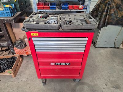 un chariot à outils rouge contenant des outils, dans un garage