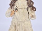 an antique doll of a woman in a white dress and bonnet