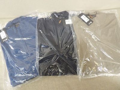 trois paires de chemises emballées dans des sacs en plastique, posées sur un canapé