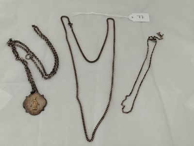 three necklaces and a key are on a white surface