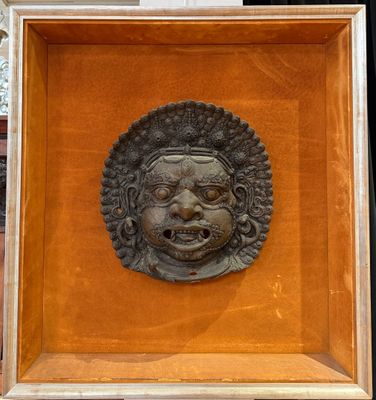 a bronze head of a man in a wooden frame