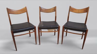trois chaises en bois dont les assises sont recouvertes de cuir noir, sur fond blanc