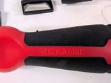 a red plastic spoon with a black handle next to a set of knives