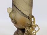 a glass vase with a bird on it on a table