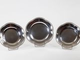 three silver plated dishes on stands on a white surface