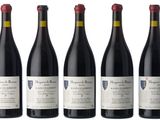 four bottles of red wine are lined up in a row