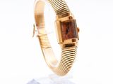 a close up of a gold wrist watch on a clear stand