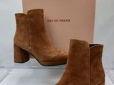 une paire de bottines en daim marron, avec une boîte en arrière-plan