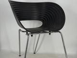 an image of a black plastic chair against a white wall