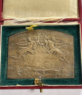 une plaque métallique dans un coffret rouge posé sur une surface blanche