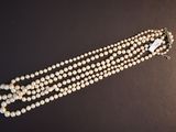 a close up of a necklace with pearls on a black surface