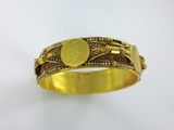 Gros plan sur un bracelet en or orné d'une pièce de monnaie
