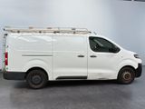 the white van is parked in a large room with a ladder on the roof