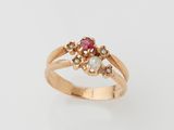 un gros plan sur une bague en or sertie d'une pierre rose et de perles