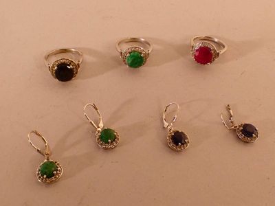 six paires de bagues ornées de pierres de différentes couleurs, posées sur un fond blanc