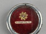 an image of a small silver and red button with a flower on it