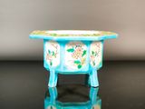une petite table bleue avec des fleurs dessus, posée sur une surface noire