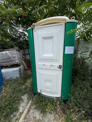 des toilettes vertes et blanches posées dans l'herbe