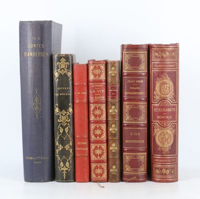 Plusieurs livres anciens sont alignés sur une étagère devant un fond blanc.