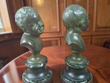 pair of bronze busts of a boy and a girl on a table
