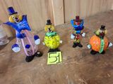 cinq figurines de clowns posées par terre les unes à côté des autres