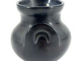 a black vase that is sitting on a white surface