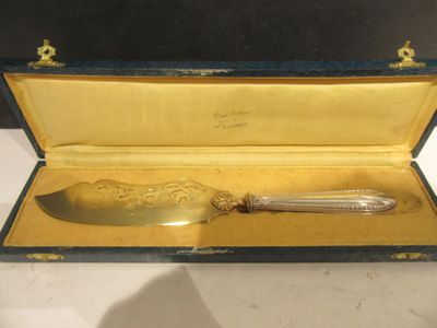 un couteau plaqué or dans un étui posé sur une table blanche