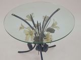a glass table with flowers on it on a white surface