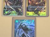 Trois cartes Pokémon différentes sont posées sur une table.