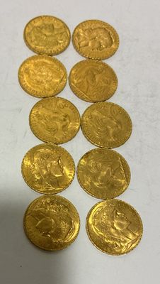 some gold coins sitting on top of a white table next to a cup
