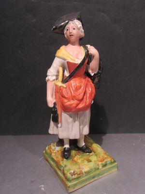 une figurine représentant une femme avec un sac, posée sur un socle