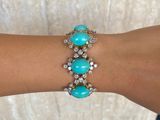 a close up of a woman ' s arm wearing a bracelet with turquoise stones