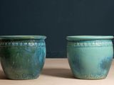 deux vases verts posés l'un à côté de l'autre sur une table