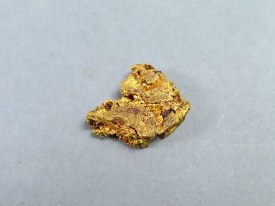 un petit morceau d'or sur une surface blanche