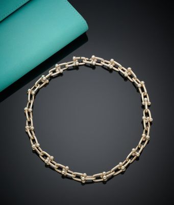 un bracelet en chaîne dorée à côté d'un sac à main bleu