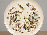 a plate with a bird and flowers on it on a table
