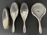 three silver spoons and a brush sitting on a table