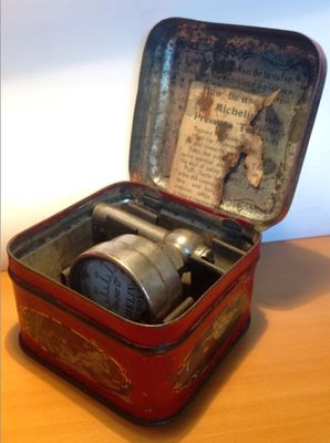 a small tin box with a clock inside of it