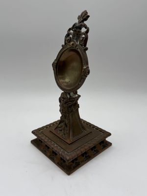 an antique bronze figurine of a woman holding a mirror