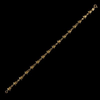 a close up of a gold star bracelet on a black background