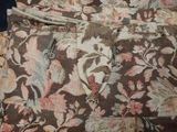 a brown and white floral print bag on a bed