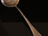 an antique silver spoon with a spoon handle sitting on a black surface
