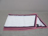 white towel with pink and black trim on a bed